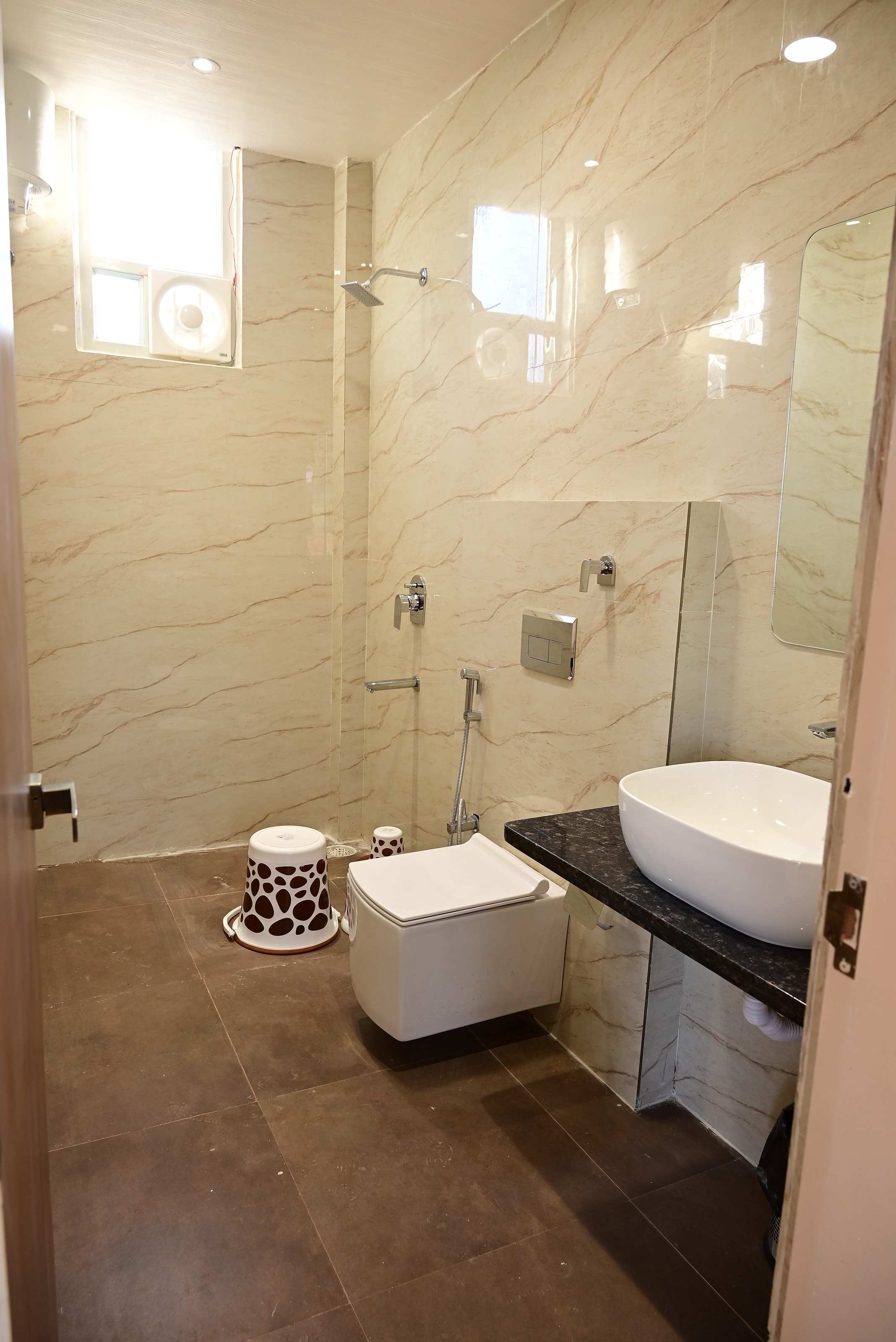 Clean bathroom with a marble-look wall, glass-screened shower, basin and wall-hung WC