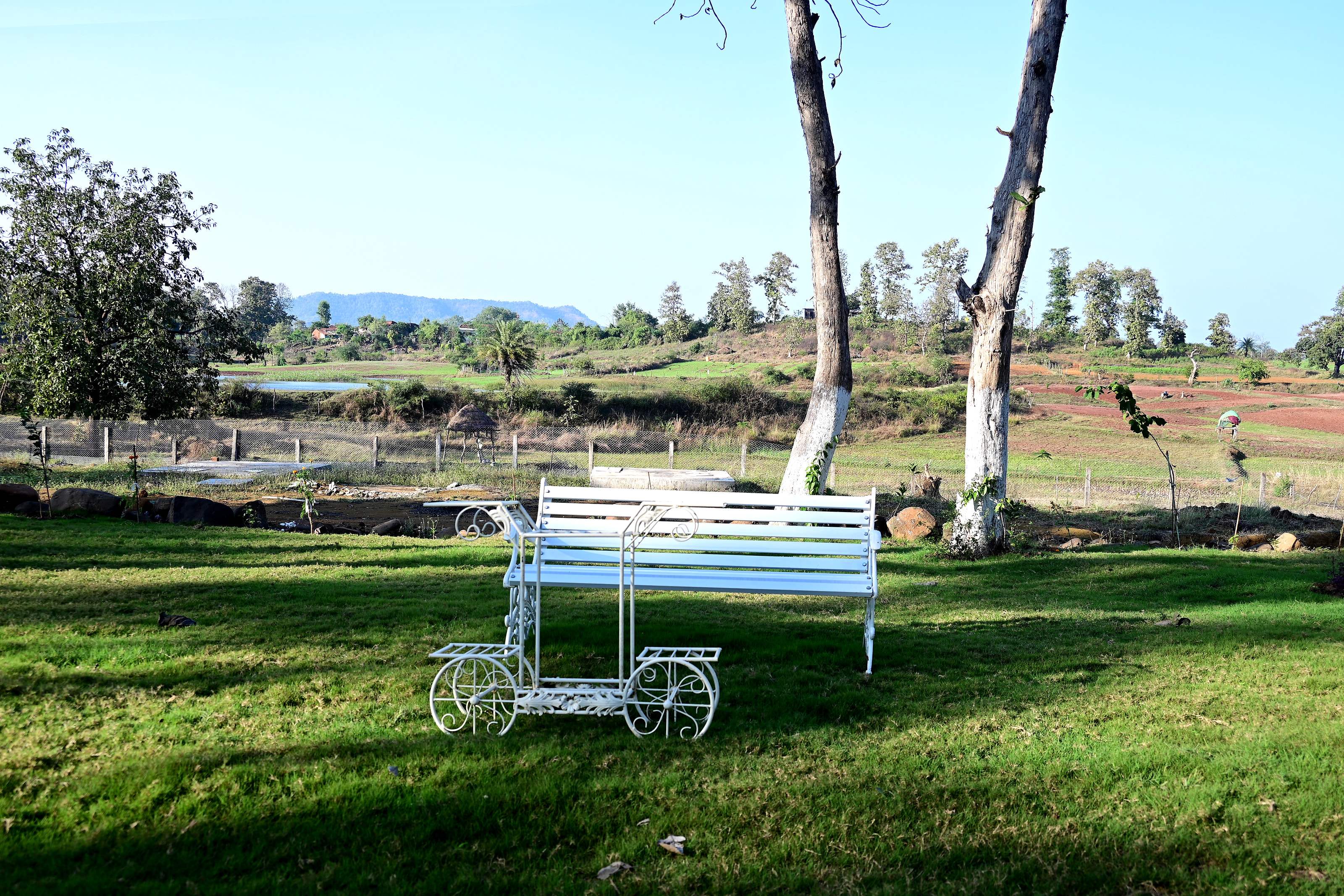 White garden bench on the lawn, looking over fields to distant hills