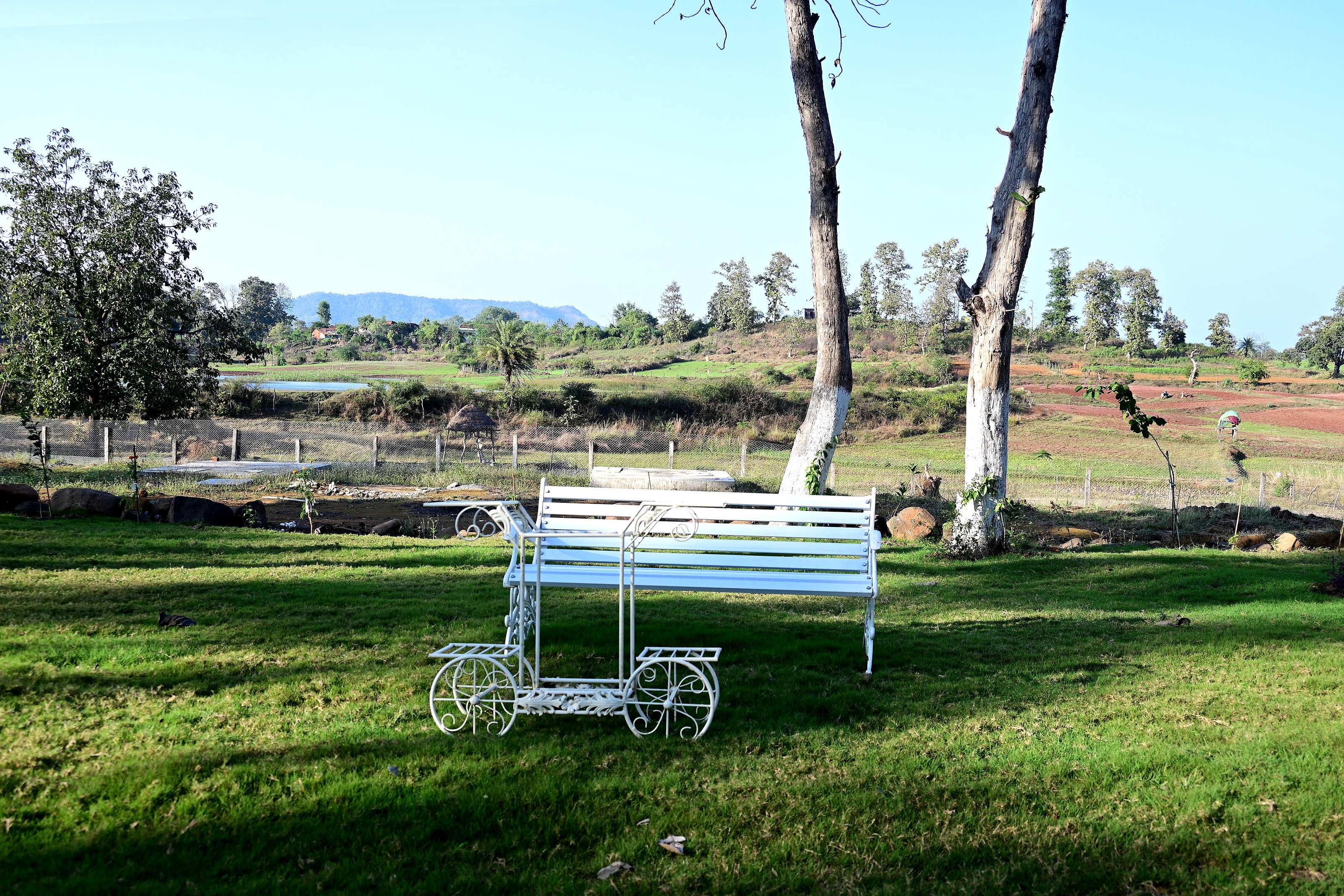 White garden bench on the lawn, looking over fields to distant hills