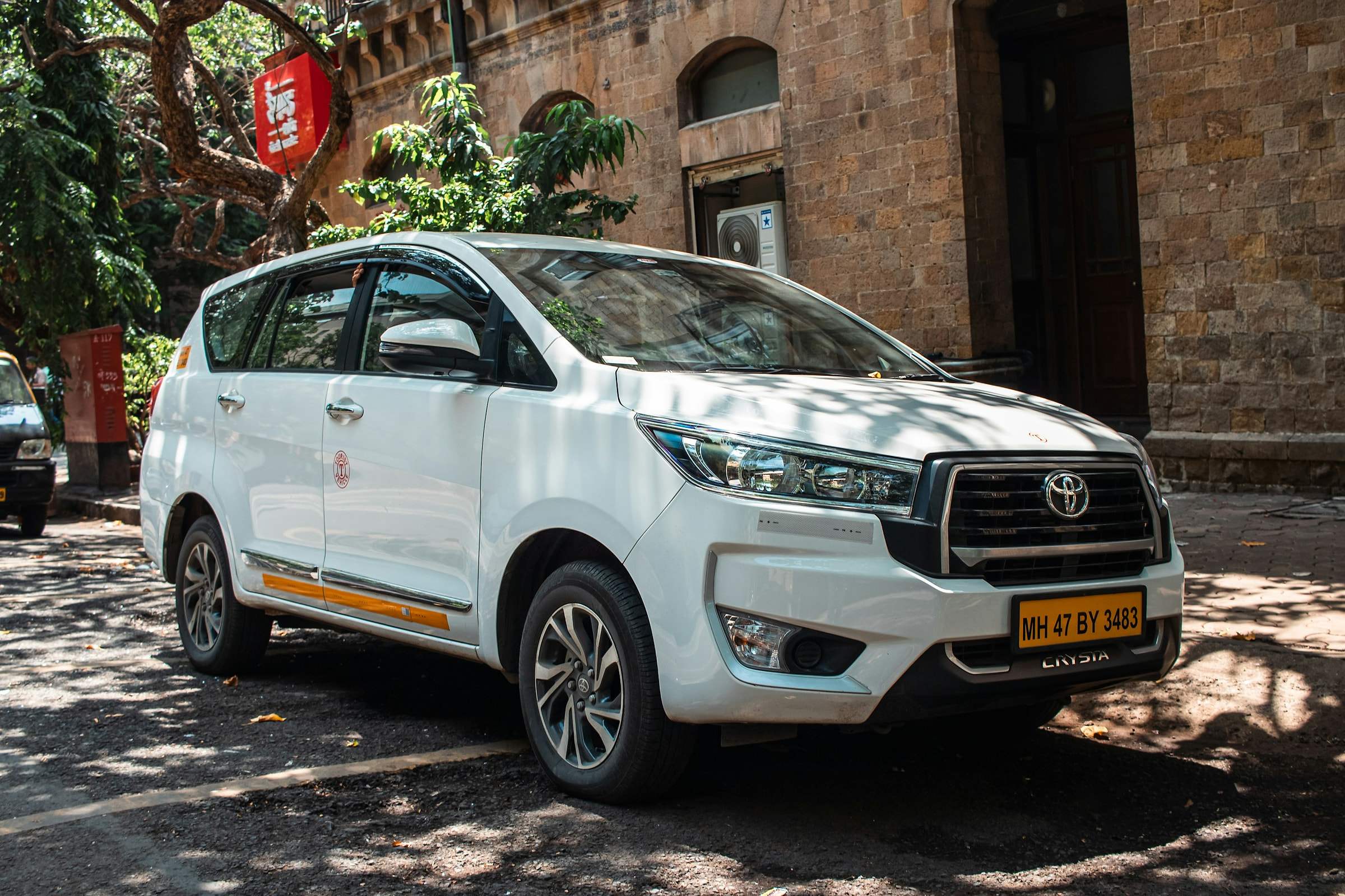 A white Toyota Innova Crysta taxi parked on a street
