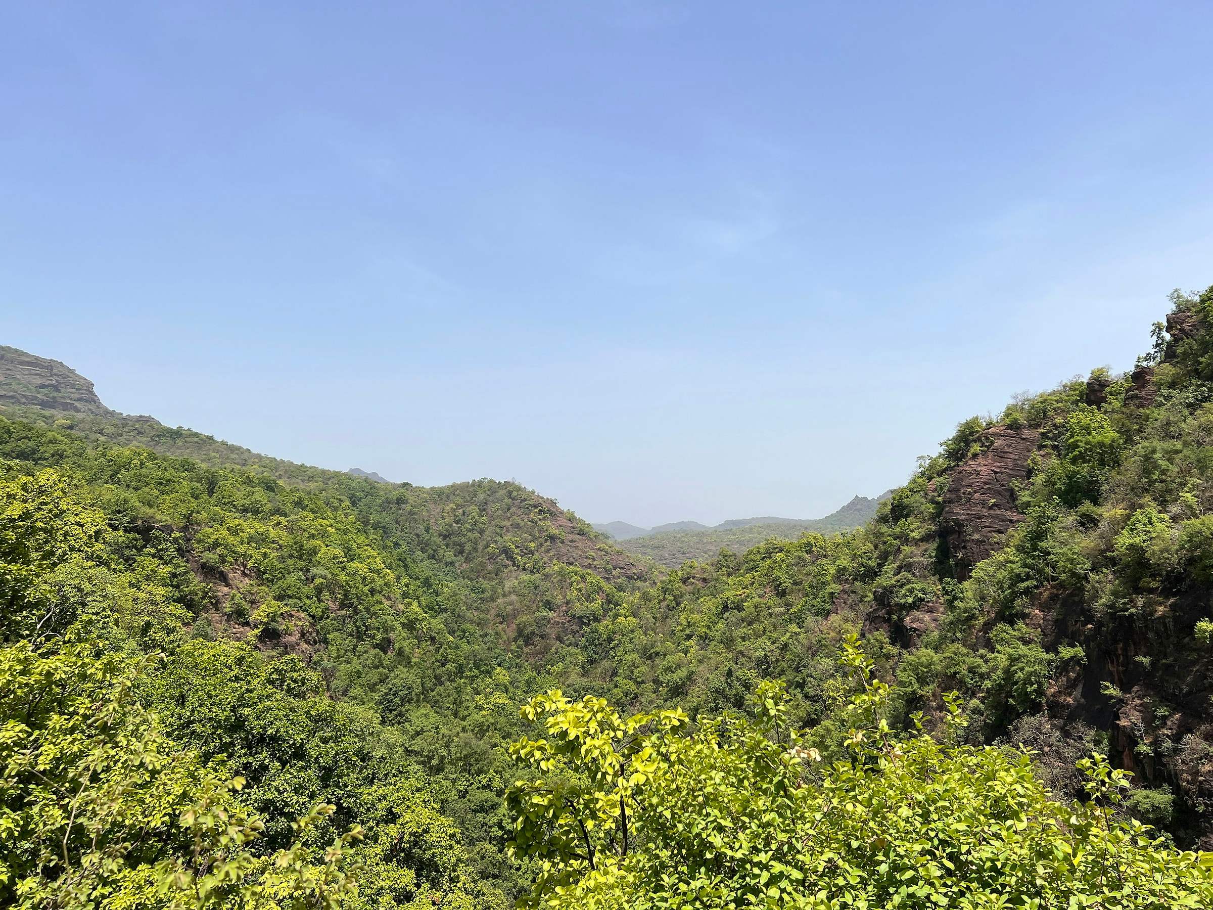 A green valley between forested hills in Pachmarhi under a clear sky