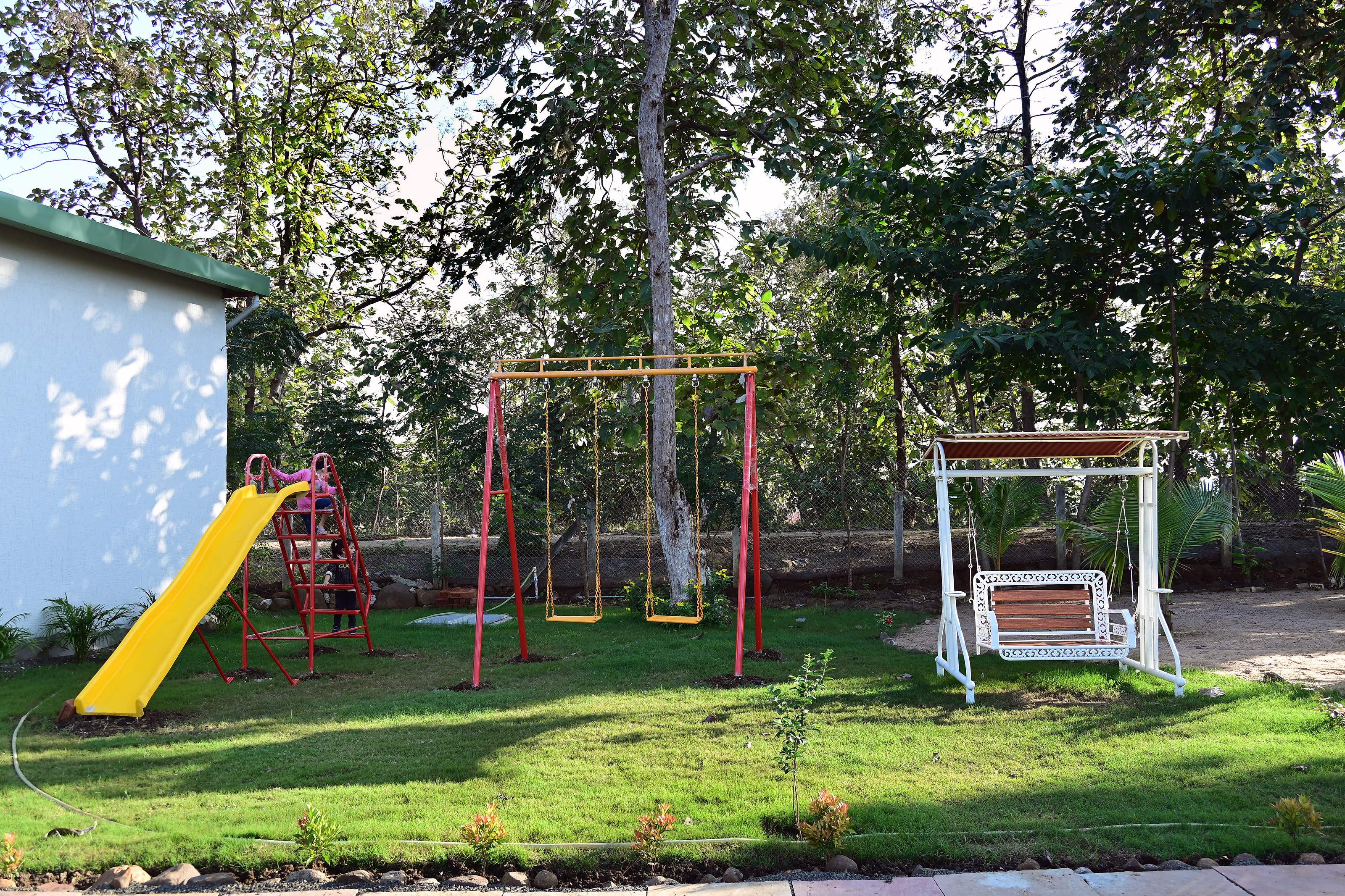 Children's play area with a slide, swings and a garden swing seat on the lawn