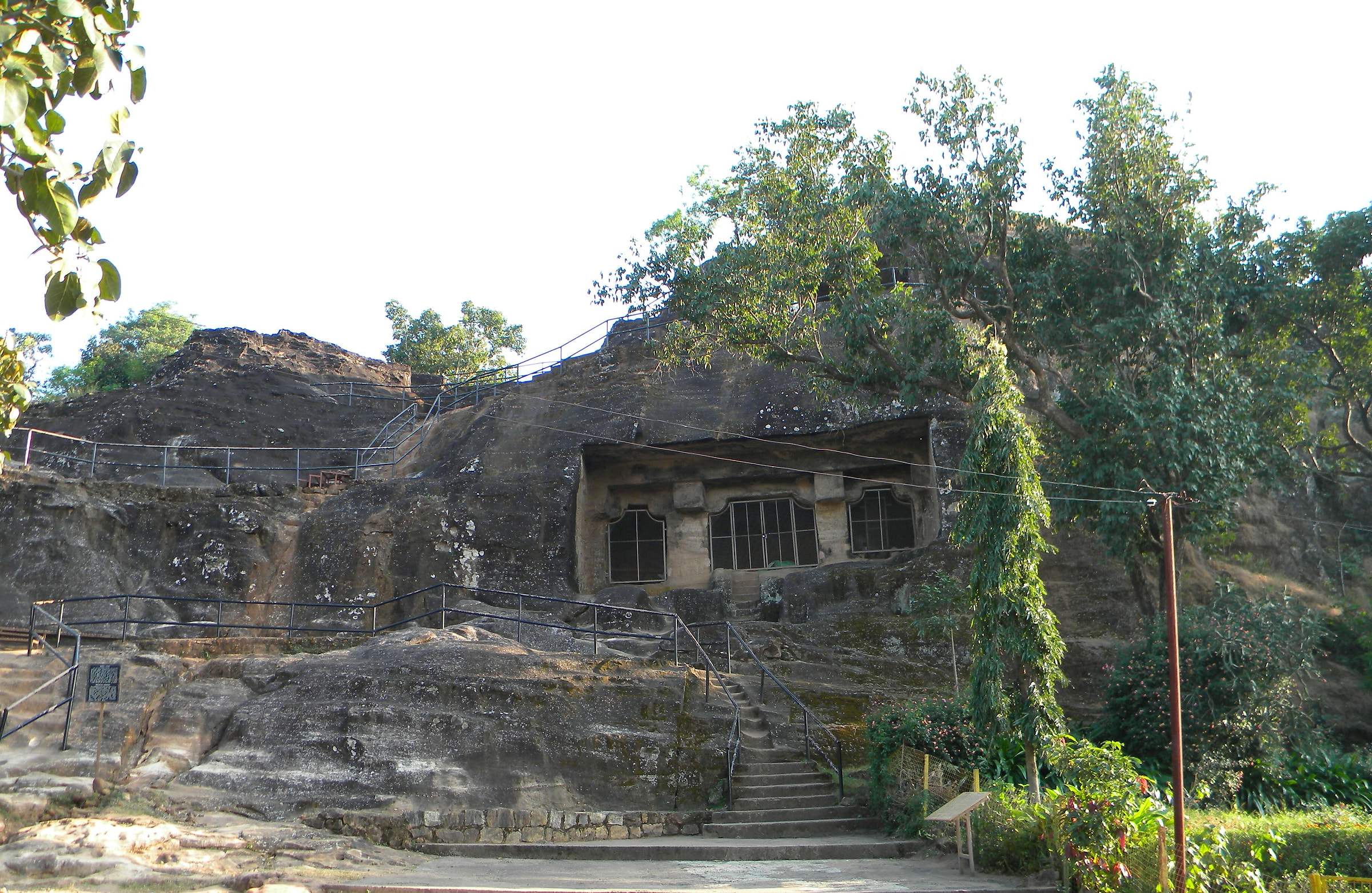 The rock-cut Pandav Caves on a sandstone hill, with steps leading up to them