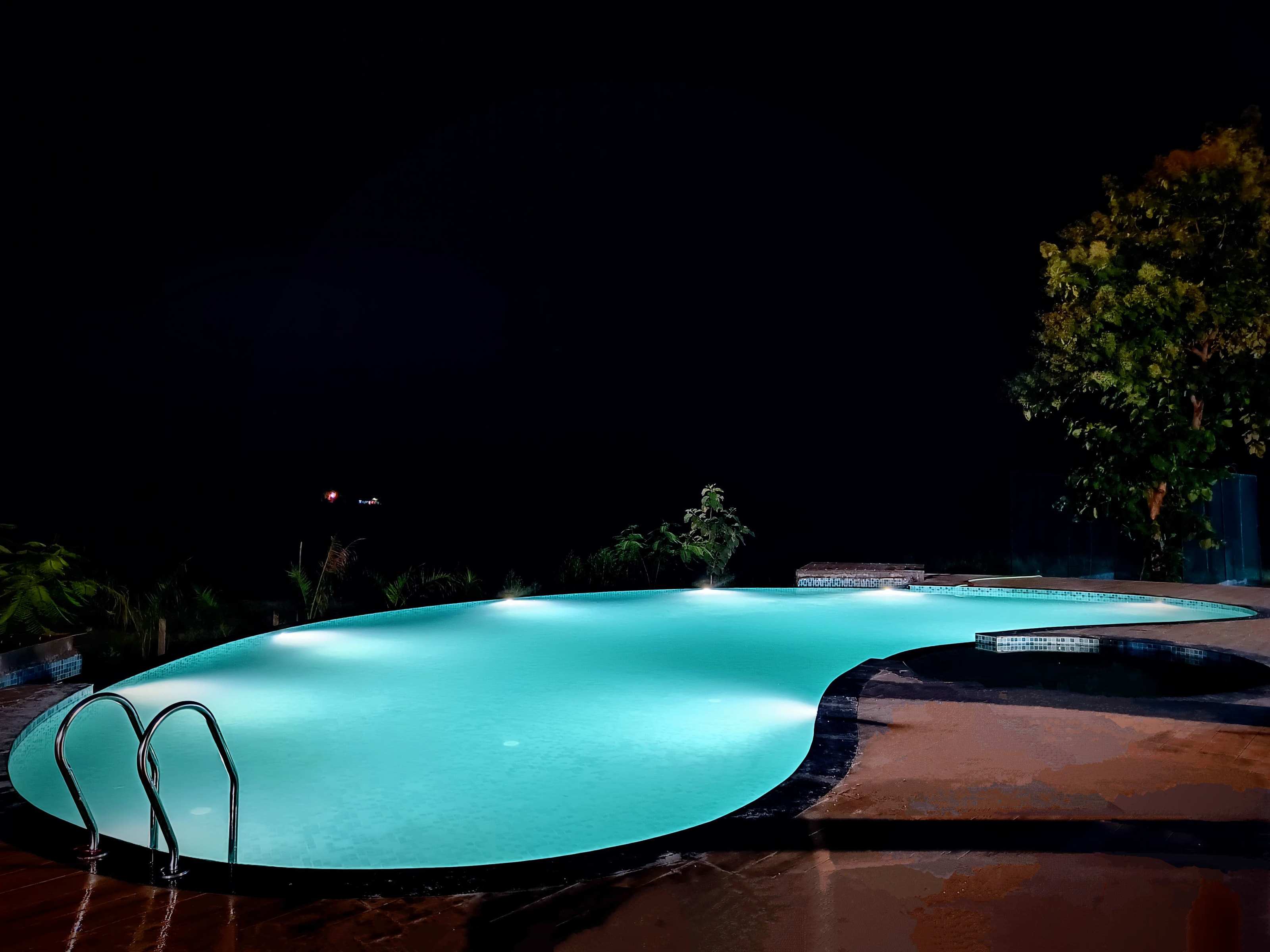 Swimming pool glowing turquoise under its lights at night