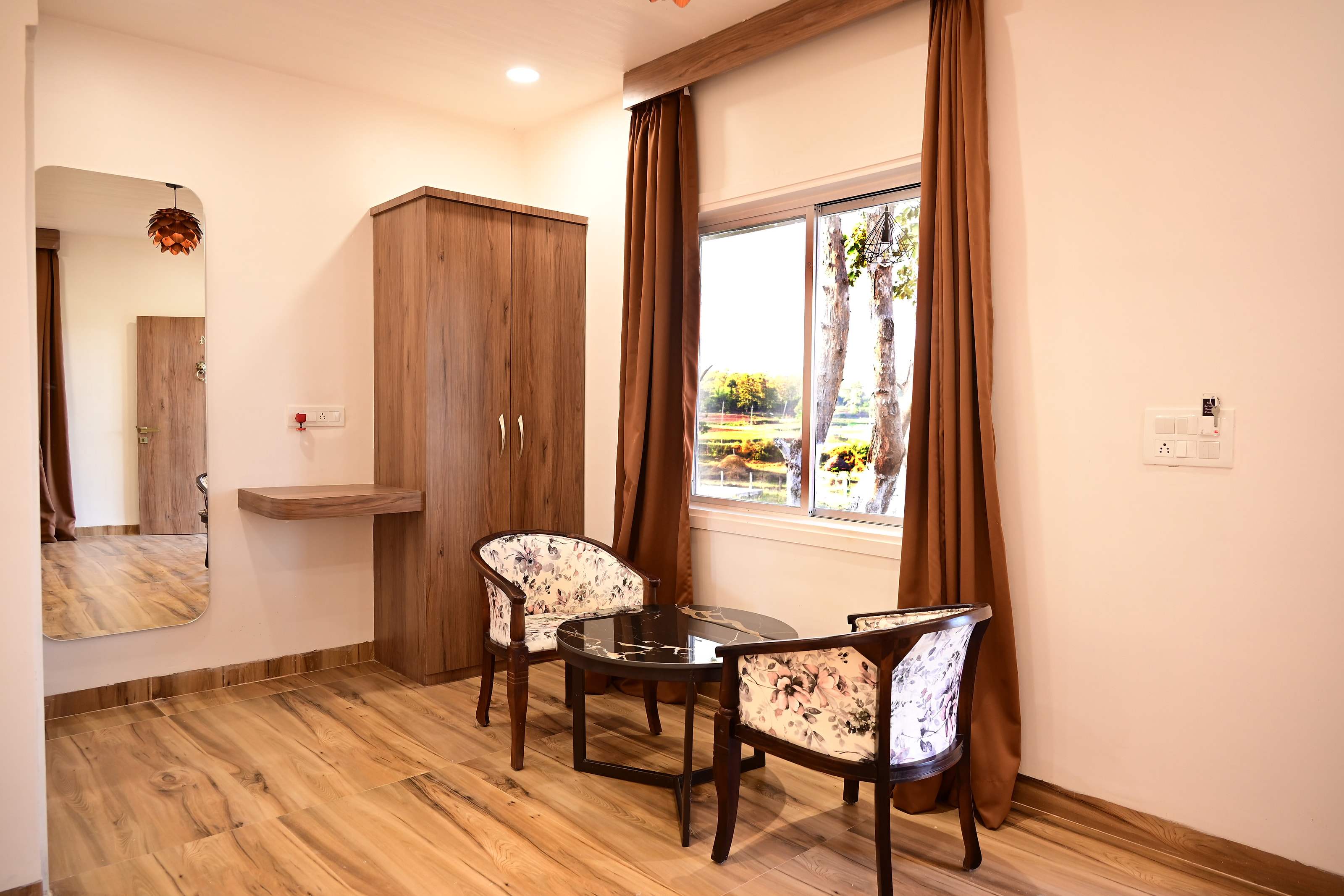Two chairs and a table by the cottage window, with wardrobe and mirror