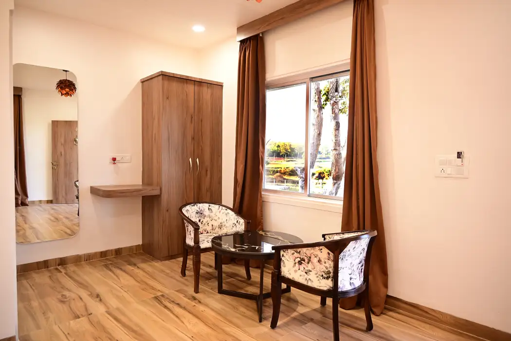 Two chairs and a table by the cottage window, with wardrobe and mirror